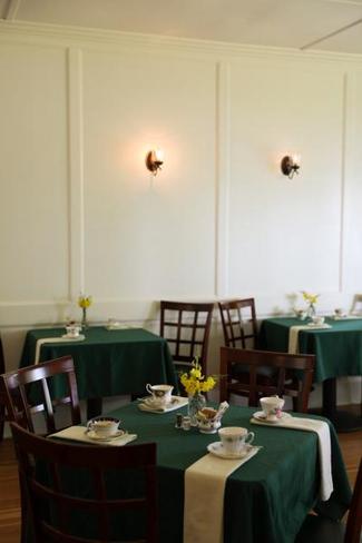 Small tables with green tablecloths and tea cups ready for tea service
