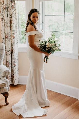 Bride posing in front of a window holding flowers.